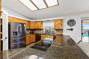 A modern kitchen with granite countertops, stainless steel appliances, wooden cabinets, and a view of the ocean. - Lake Havasu Retreat w Private Pool & Spa, Lake Views + Boat Parking (Lake Havasu City)
