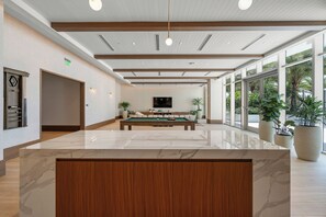 A spacious indoor area with a pool table, a large potted plant, and a television mounted on the wall. - Brand-New Furnished Luxury, Sophisticated Turnkey at a Premier Address (North Miami)