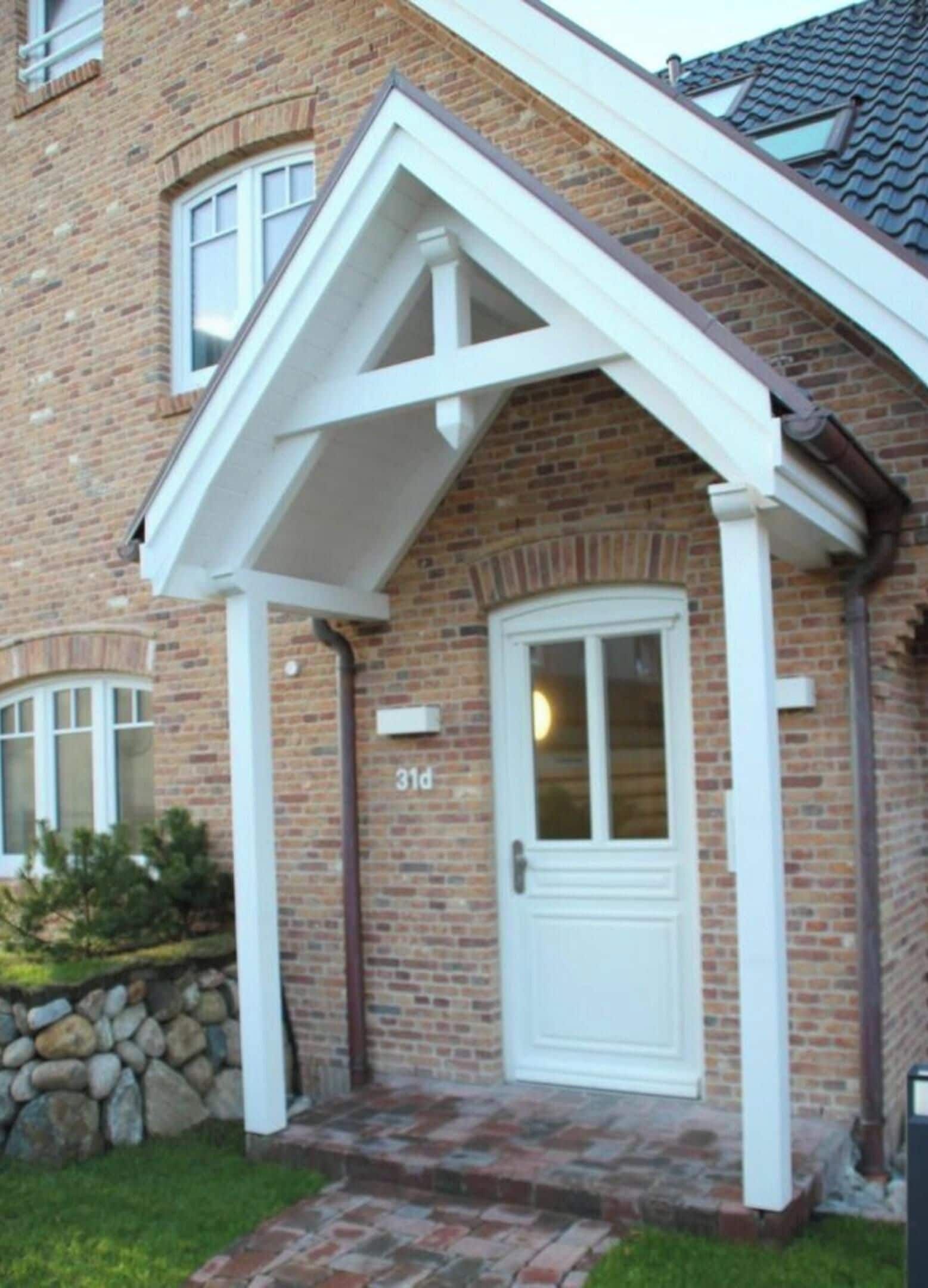 A brick house with a white front door, a small porch, and a number '31a' on the wall.