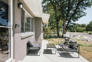 Ein Gebäude mit einer überdachten Terrasse, die Sitzgelegenheiten mit Kissen und einen Tisch bietet.