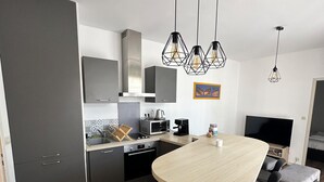 Een moderne keuken met een centraal eiland, zwarte barkrukken en hanglampen.