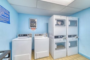 A laundry room with stacked washers and dryers, a notice sign, and a blue wall. - Elevated Seaside Sanctuary With Beach Gear (Hilton Head Island)