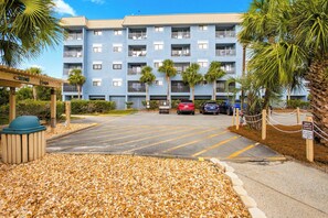 A multi-story building with a parking lot in front, surrounded by palm trees and a sign warning of an alligator. - Elevated Seaside Sanctuary With Beach Gear (Hilton Head Island)