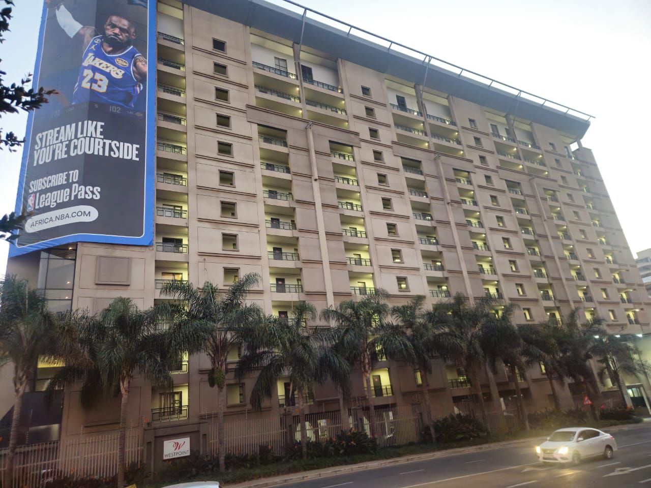 A multi-story hotel with balconies and a large billboard advertising NBA streaming.