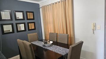 A dining area with a dark wooden table, six chairs, and a bowl of snacks.
