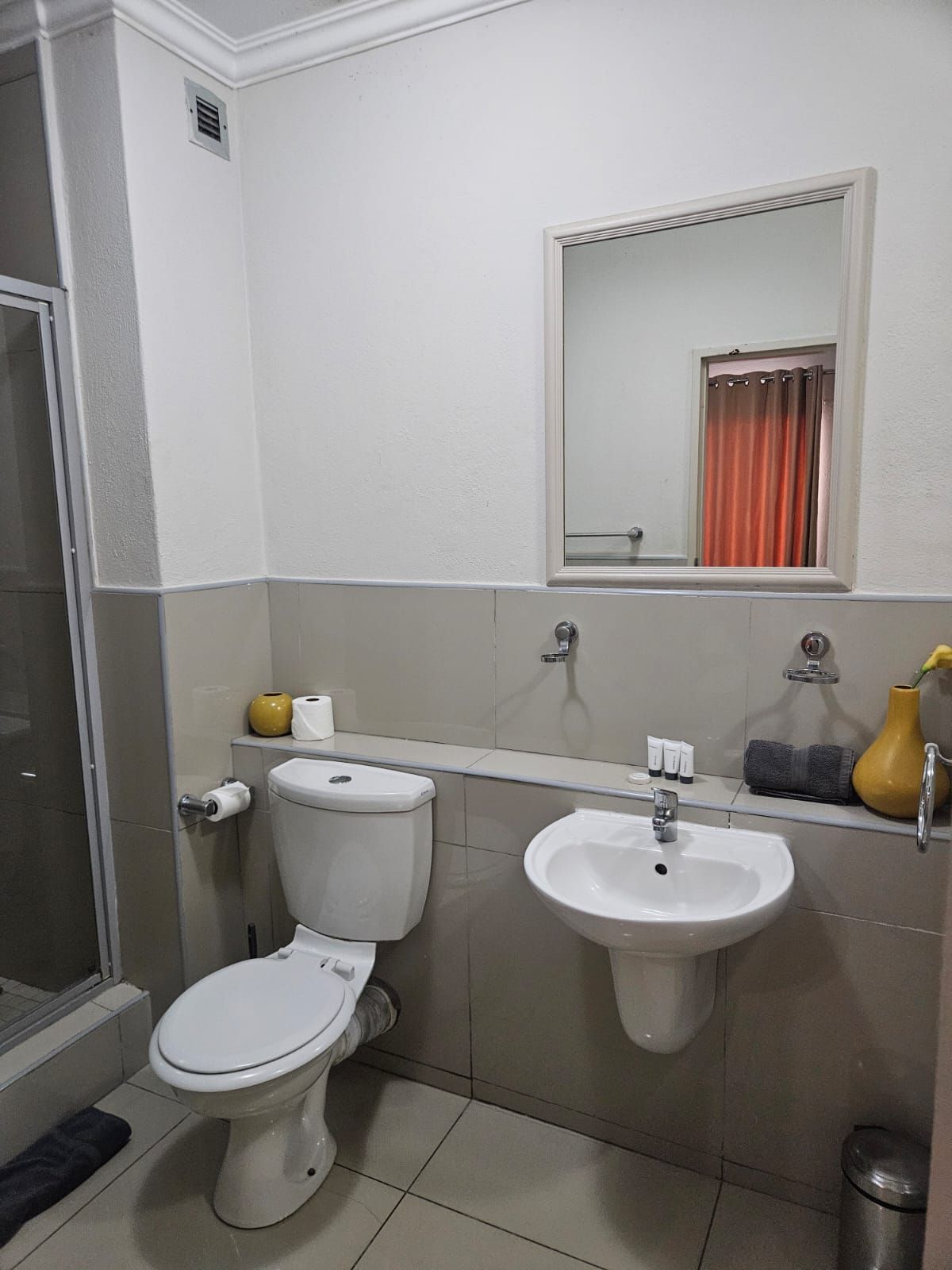 Un baño con inodoro, lavamanos y espejo sobre él.