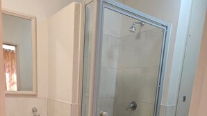 A bathroom with a glass-enclosed shower, a sink with a marble countertop, and wooden cabinets. - Sandton Westpoint Luxury Apartments -172 (Sandton)