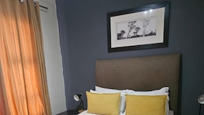 A neatly made bed with white and yellow pillows, a grey blanket, and a rolled white towel on the side. - Sandton Westpoint Luxury Apartments -172 (Sandton)