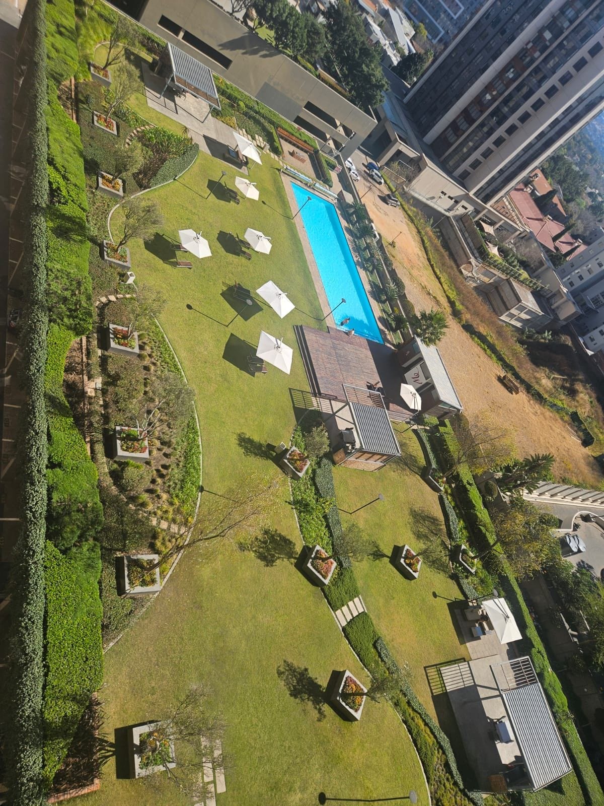 Vista aérea de una zona residencial con piscina, césped verde y algunos edificios.