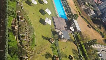 Vista aérea de una zona residencial con piscina, césped verde y algunos edificios.