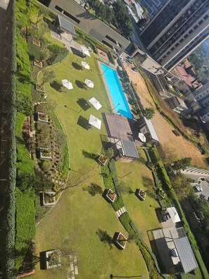 An aerial view of a residential area with a swimming pool, green lawns, and a few buildings. - Sandton Westpoint Luxury Apartments -172 (Sandton)