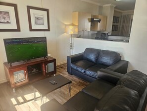 A living room with a television, a sofa, a coffee table, and a lamp. - Sandton Westpoint Luxury Apartments -172 (Sandton)