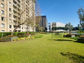 A well-maintained courtyard with a lawn, seating areas, and a pool. - Sandton Westpoint Luxury Apartments -172 (Sandton)