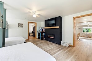 Ein Zimmer mit zwei Betten, einem Kamin, einem Fernseher und einer Essecke mit Tageslicht.