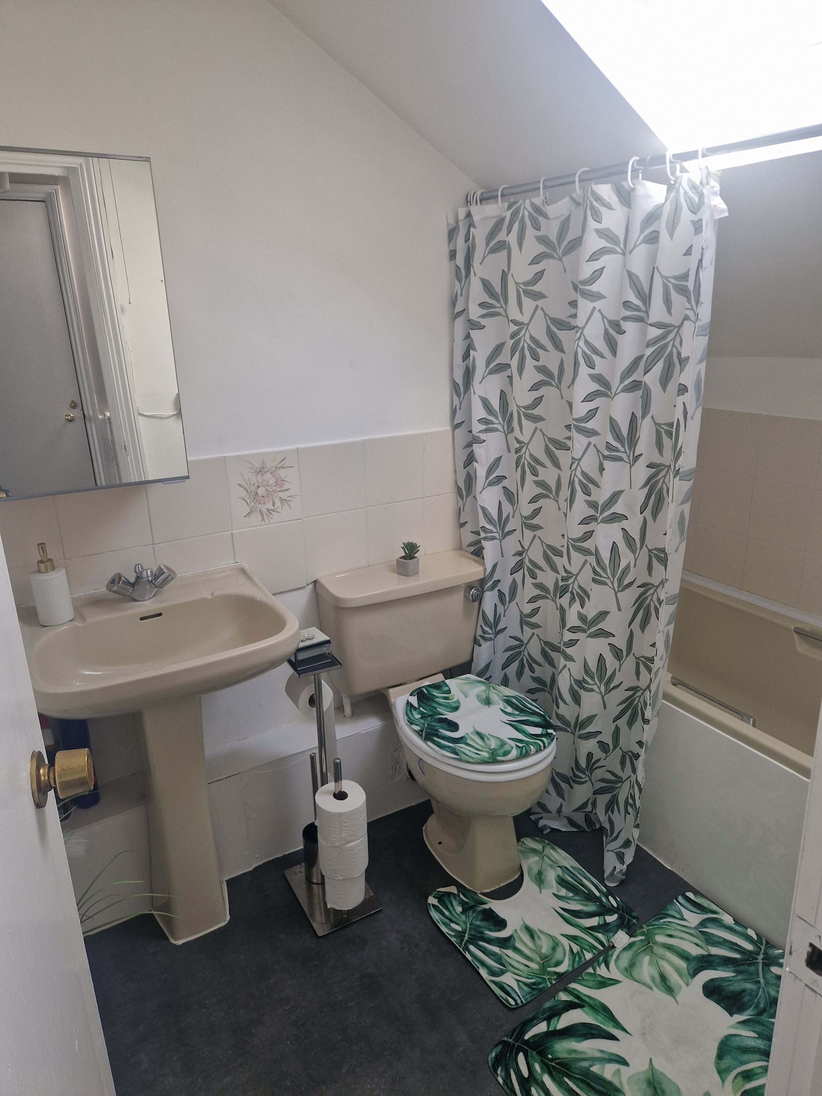 A small bathroom with a toilet, sink, and shower curtain.