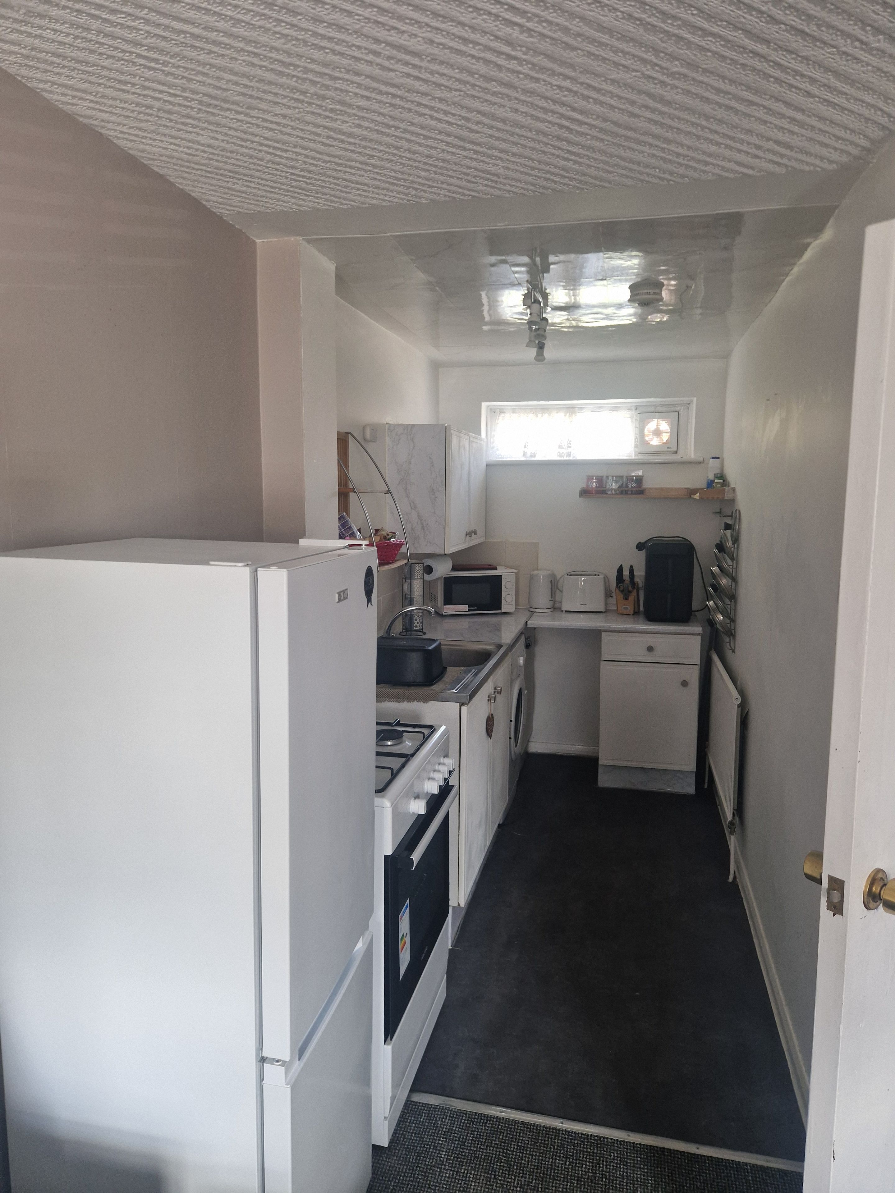 A compact kitchen with a refrigerator, stove, microwave, and sink.