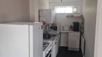A compact kitchen with a refrigerator, stove, microwave, and sink.