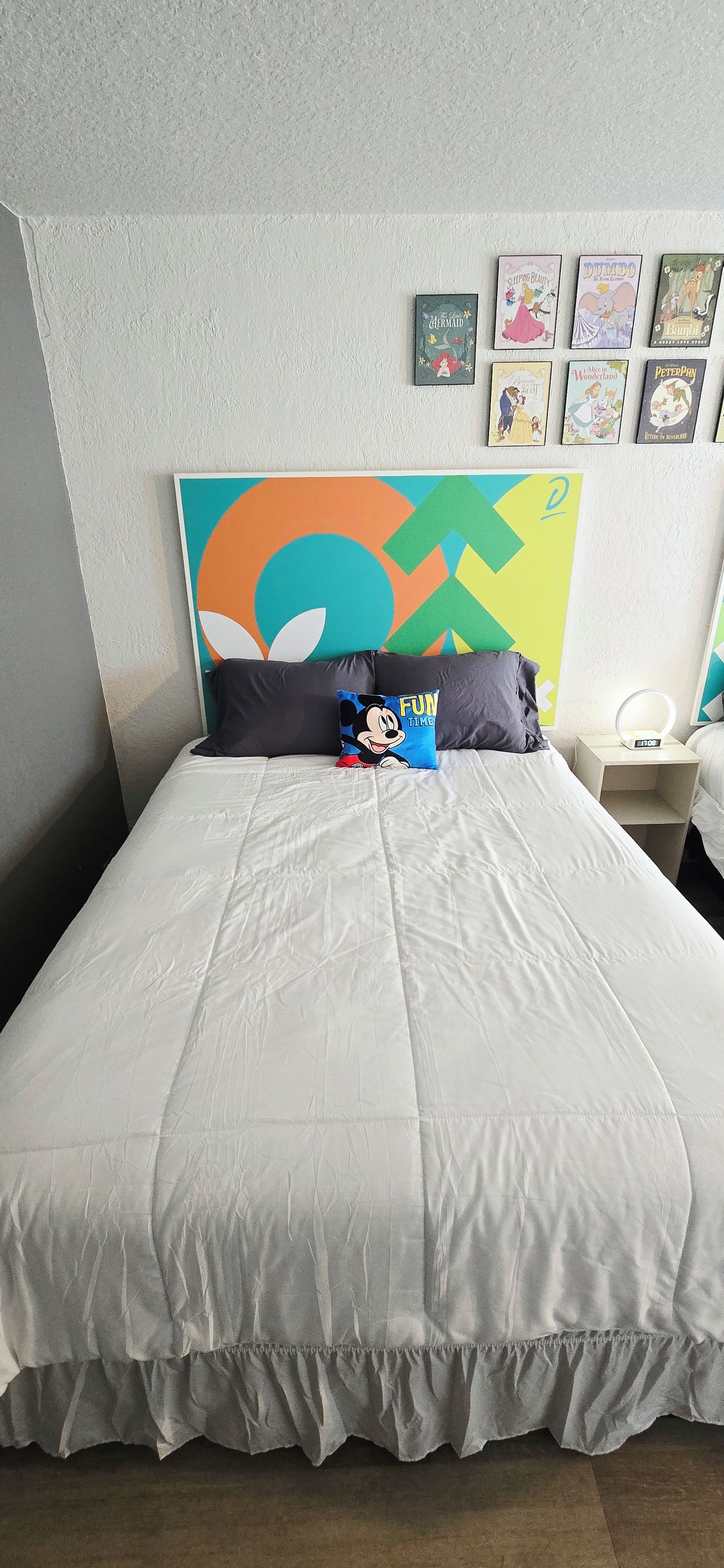 Une chambre à coucher avec un lit, des oreillers, une horloge murale et des tableaux encadrés.