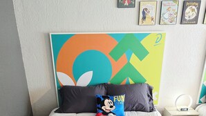 A bedroom with a bed, pillows, a wall clock, and framed pictures. - Cozy 2-Queen Room, Pool, Near Disney & Attractions. (Kissimmee)