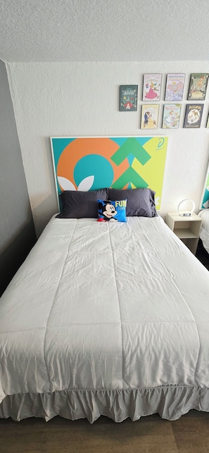 Une chambre à coucher avec un lit, des oreillers, une horloge murale et des tableaux encadrés.