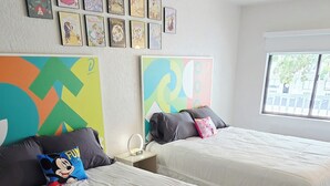 Ein Hotelzimmer mit zwei Betten, einem farbenfrohen abstrakten Gemälde und einem Fenster mit Blick.