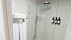 Ein modernes Badezimmer mit einer Duschkabine, einer weißen Toilette und einer Badewanne mit Glasabtrennung.