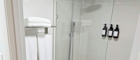 A modern bathroom with a glass-enclosed shower, a white toilet, and a glass-enclosed bathtub.