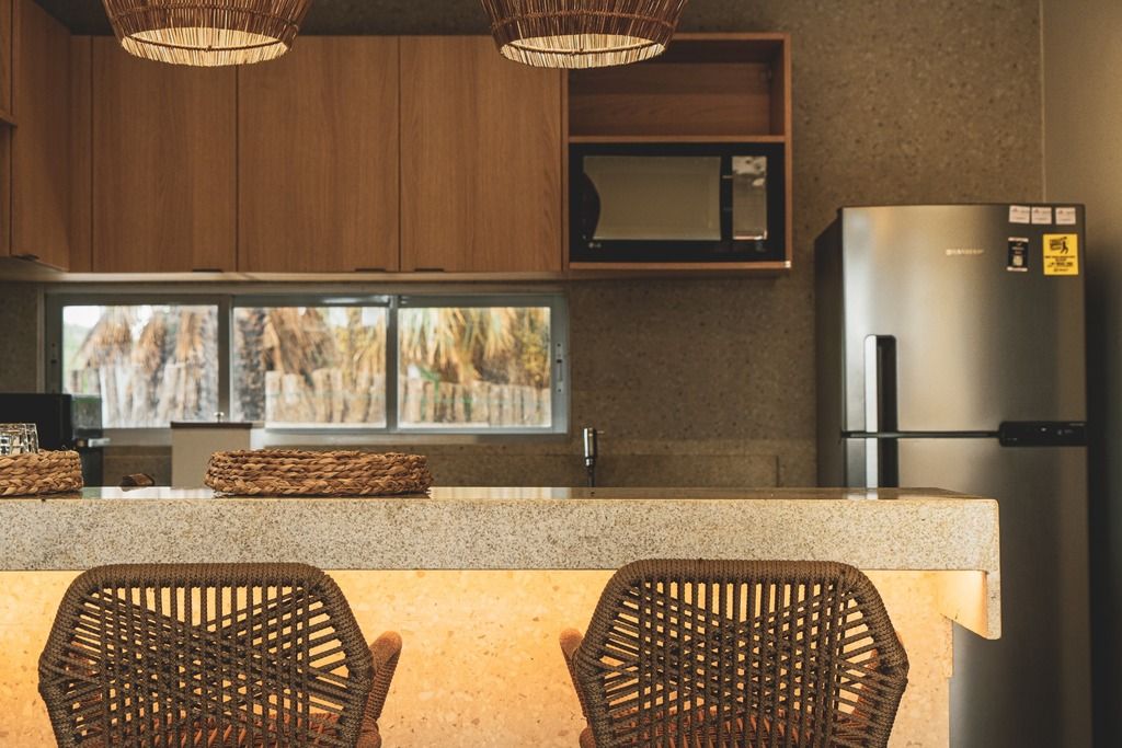 Une cuisine avec des meubles en bois, un réfrigérateur en acier inoxydable et une fenêtre donnant sur les arbres.