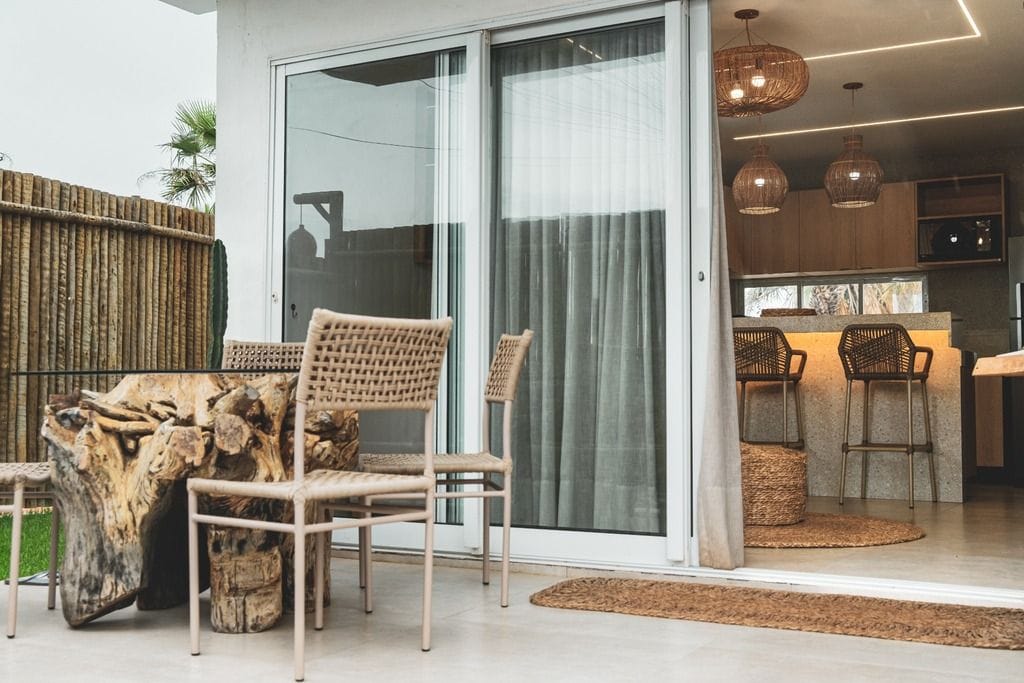 A modern kitchen with wooden cabinets, a bar area, and a sliding glass door leading to a patio with outdoor furniture.