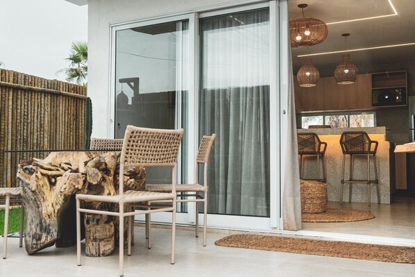 A modern kitchen with wooden cabinets, a bar area, and a sliding glass door leading to a patio with outdoor furniture.