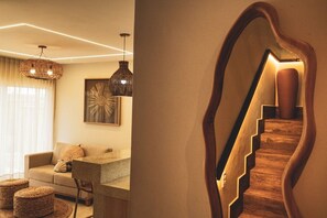 A modern interior with a staircase, a sofa, a dining table, and pendant lighting.