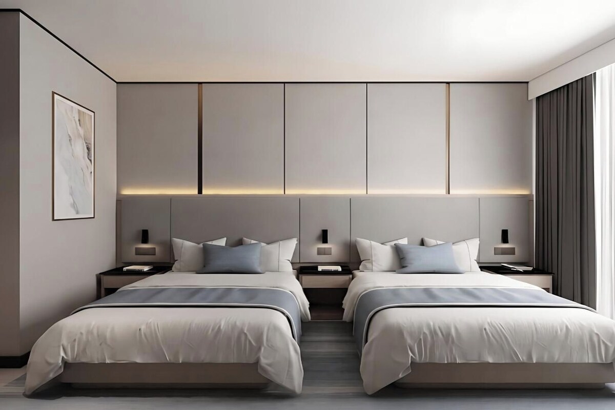 Un dormitorio moderno con dos camas, mesitas de noche y un amplio ventanal con cortinas.