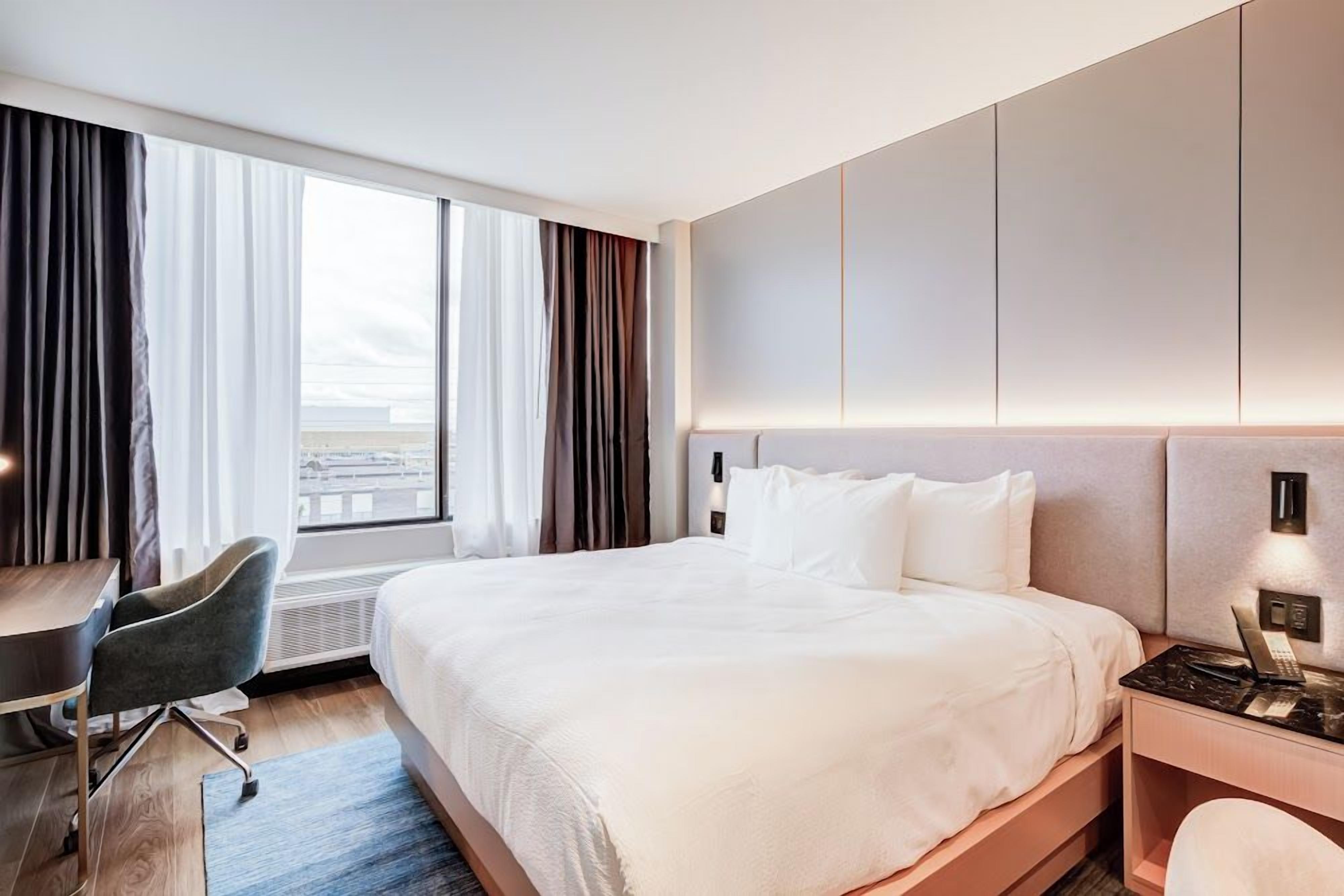 A hotel room with a large bed, a desk, and a chair.