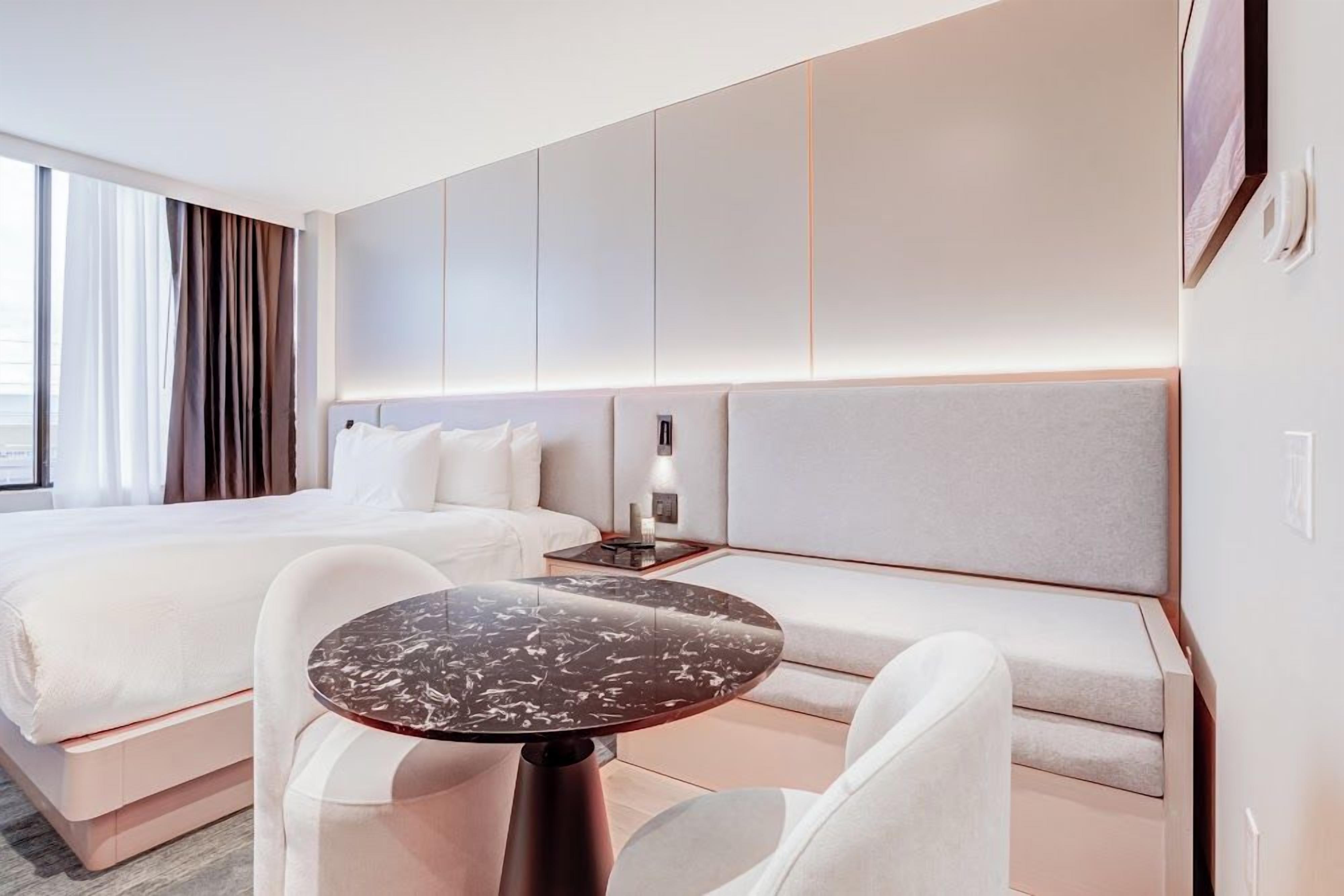 Une chambre d’hôtel moderne avec un grand lit, un canapé, une table ronde et une table de chevet.