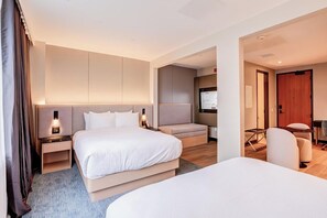 Una habitación de hotel con una cama grande, una cama más pequeña, un escritorio y una silla.