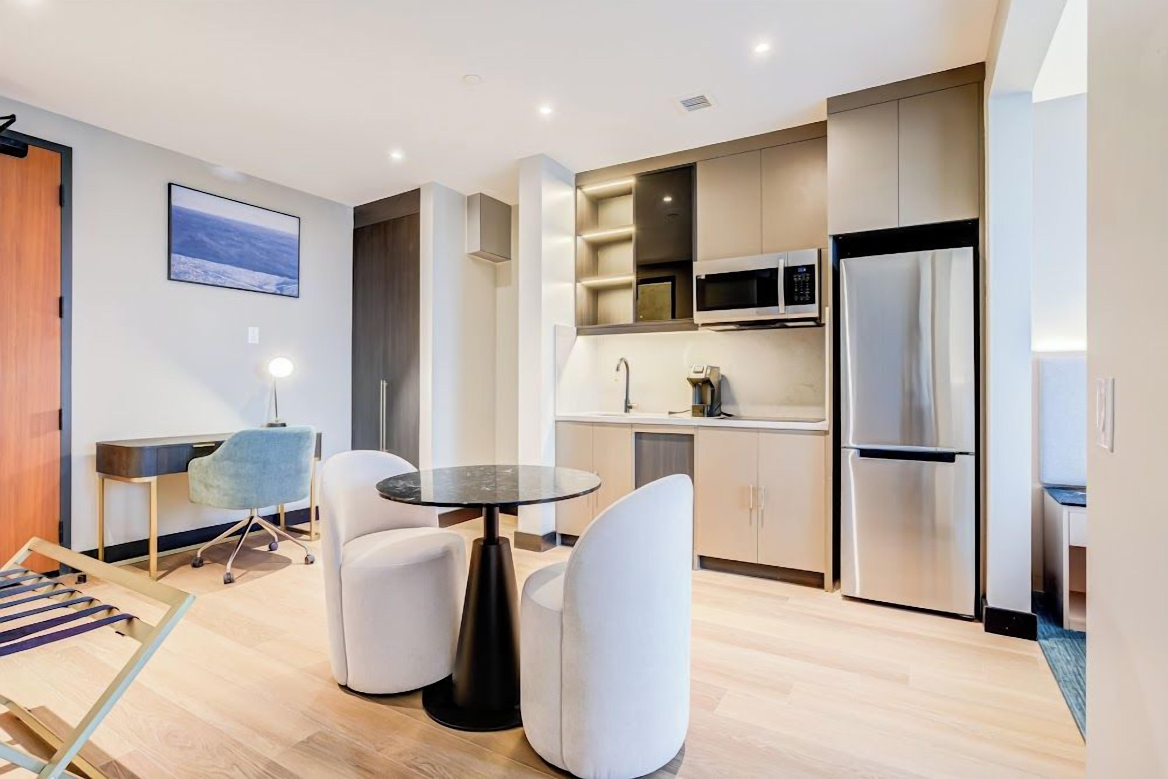 A modern kitchen with a dining area, including a round table and chairs, and a built-in microwave.