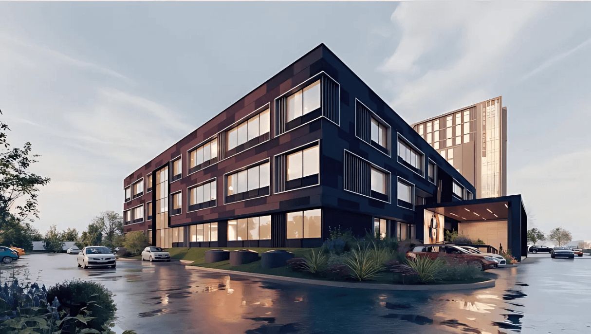 Un edificio moderno con varios pisos, ventanas amplias y un estacionamiento lleno de coches.