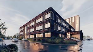 A modern building with multiple floors, large windows, and a parking lot with cars. - Aura Hotel & Suites (Mississauga)