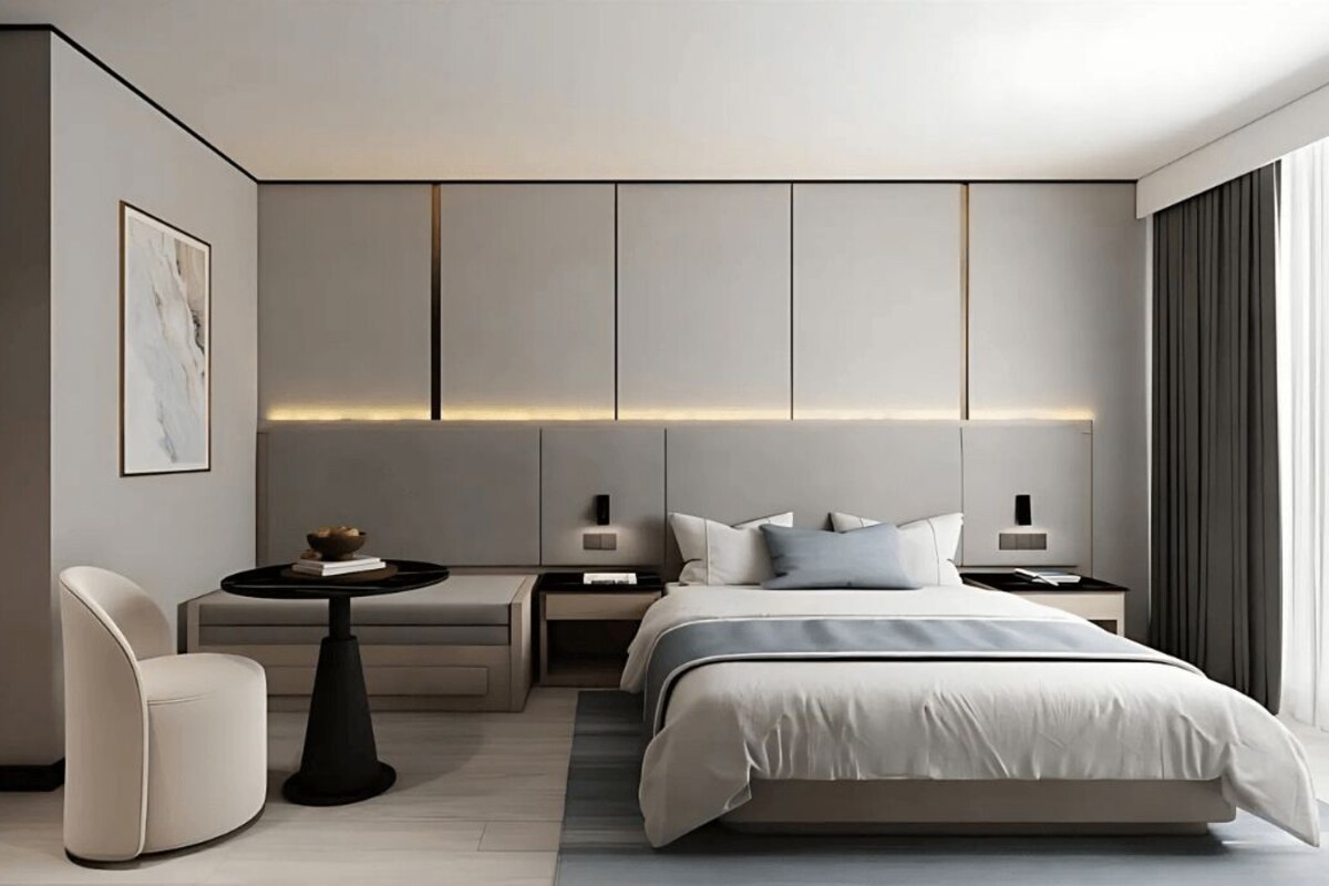 Una habitación de hotel moderna con una cama, mesitas de noche, una silla y una pequeña mesa.