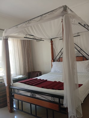 A four-poster canopy bed with a wooden frame and white bedding.