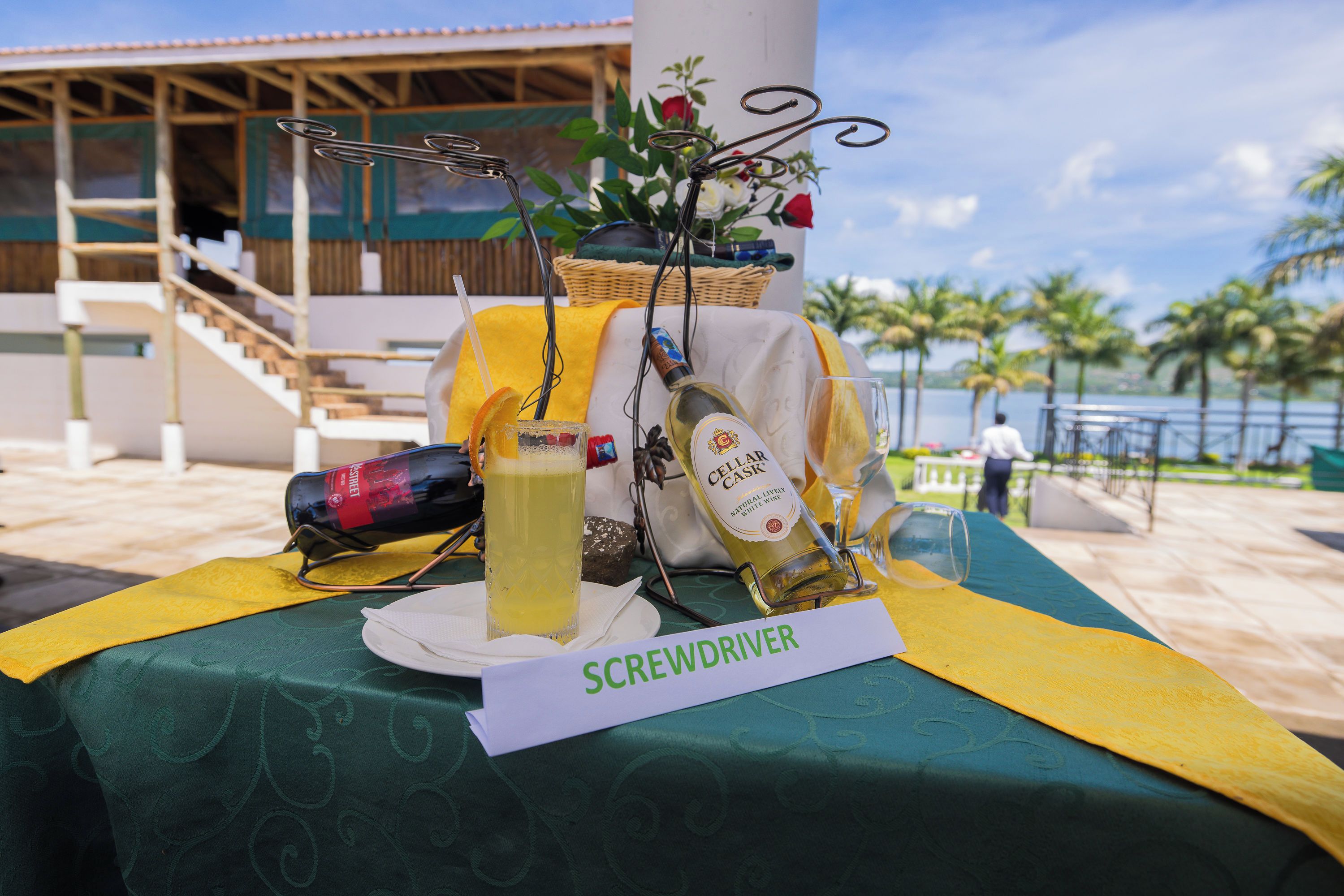 A table set with a bottle of wine, a glass of white wine, a bottle of beer, a glass of beer, and a sign reading 'Screwdriver'.