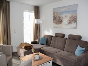 Ein modernes Wohnzimmer mit einer Couch, einem Couchtisch und einem Bild an der Wand.