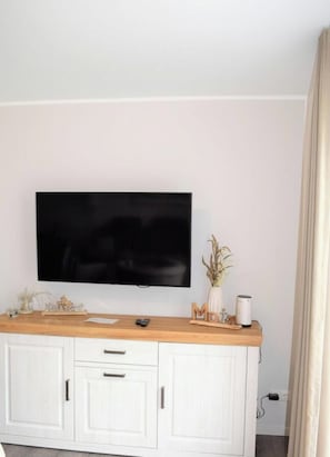 A flat-screen TV mounted on a white cabinet with a wooden countertop above it. - House No. 25, Holiday Home Fischerhus (Wangerland)