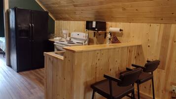 A kitchen with a wooden island, bar stools, a refrigerator, and a stove.