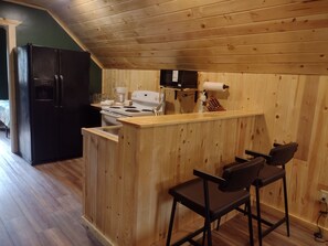 A kitchen with a wooden island, bar stools, a refrigerator, and a stove.