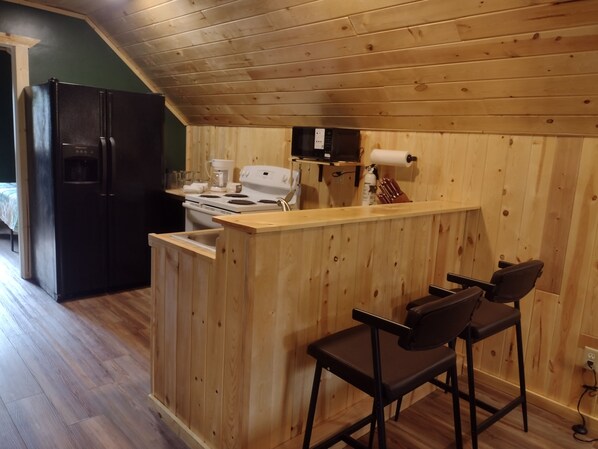 A kitchen with a wooden island, bar stools, a refrigerator, and a stove.