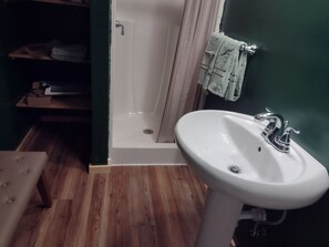 A bathroom with a white sink, a bathtub, and a wooden floor. - Welcoming 1-bedroom apartment in charming Squaw Lake (Squaw Lake)