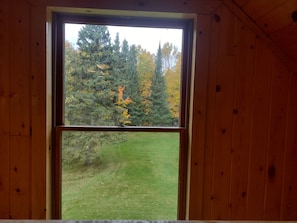 A window with a view of a forest and a grassy field.
