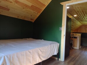 A bedroom with a bed, a wooden ceiling, and a green wall. - Welcoming 1-bedroom apartment in charming Squaw Lake (Squaw Lake)