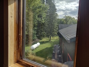 A window view of a wooden structure with a green lawn and trees. - Welcoming 1-bedroom apartment in charming Squaw Lake (Squaw Lake)
